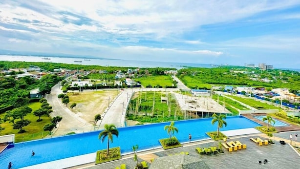 A rooftop pool with a view of a coastal cityscape, including a marina and residential areas. - 8 Newtown Boulevard by HiveRooms (Lapu-Lapu)