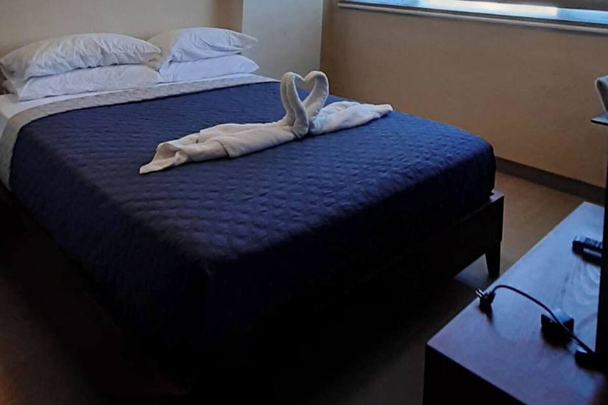 Una habitación de hotel con cama, escritorio y ventana con persianas.