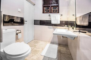 A modern bathroom with a toilet, sink, and glass shower enclosure. - Beru Villa (Beruwala)