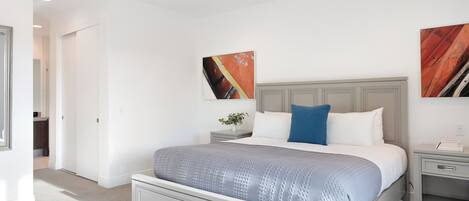 A bedroom with a bed, a nightstand, a ceiling fan, and artwork on the walls.