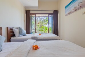 Una camera d'albergo con due letti, una grande finestra con tende e un quadro appeso al muro.