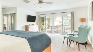 A hotel room with a bed, a desk, a chair, a TV, and a balcony with a table and chairs. - Retro Oasis w/ Pool, Ping Pong, & Large Yard | Lloyd by AvantStay Permit#3779 (Palm Springs)