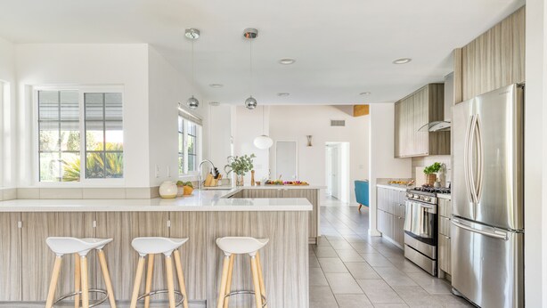 A modern kitchen with a central island, bar stools, stainless steel appliances, and a view of the outdoors. - Retro Oasis w/ Pool, Ping Pong, & Large Yard | Lloyd by AvantStay Permit#3779 (Palm Springs)