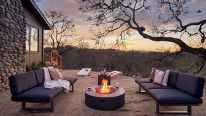 A stone building with a fire pit in the center, surrounded by two sofas and a table with a game. - 3.5-Acre 5BDR Rereat w/ Views, Pool + Hot Tub, Fire Pit | Gable by AvantStay (Santa Rosa)