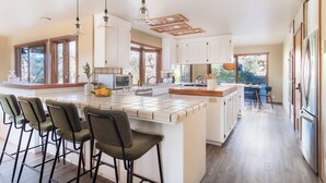 A modern kitchen with a large island, bar stools, and pendant lighting. - 3.5-Acre 5BDR Rereat w/ Views, Pool + Hot Tub, Fire Pit | Gable by AvantStay (Santa Rosa)