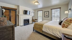 Een slaapkamer met een open haard, een bed, een stoel en een televisie.