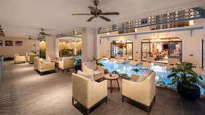 A spacious indoor area with a pool, wicker furniture, and a dining area visible through glass doors. - Amina Lantana Hoi An Hotel & Spa (Da Nang)