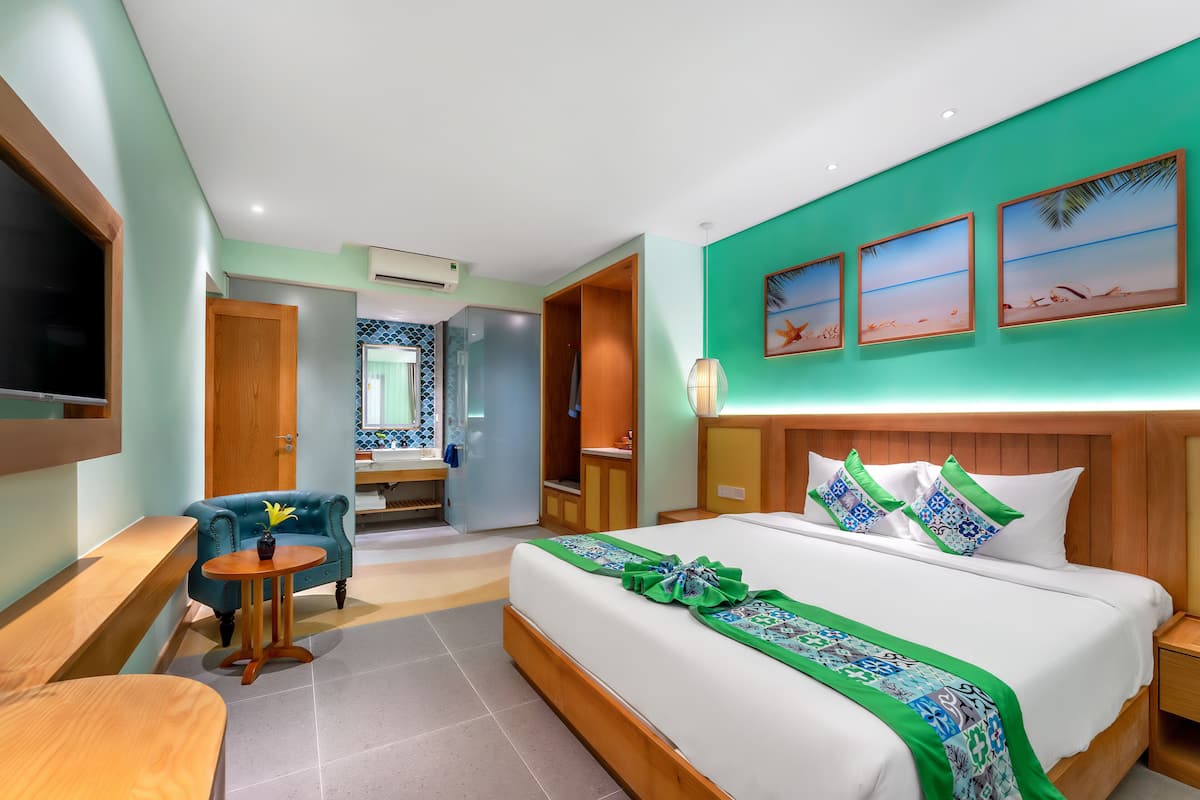 Hotelkamer met een bed, bureau, stoel, badkamer en uitzicht op het strand.