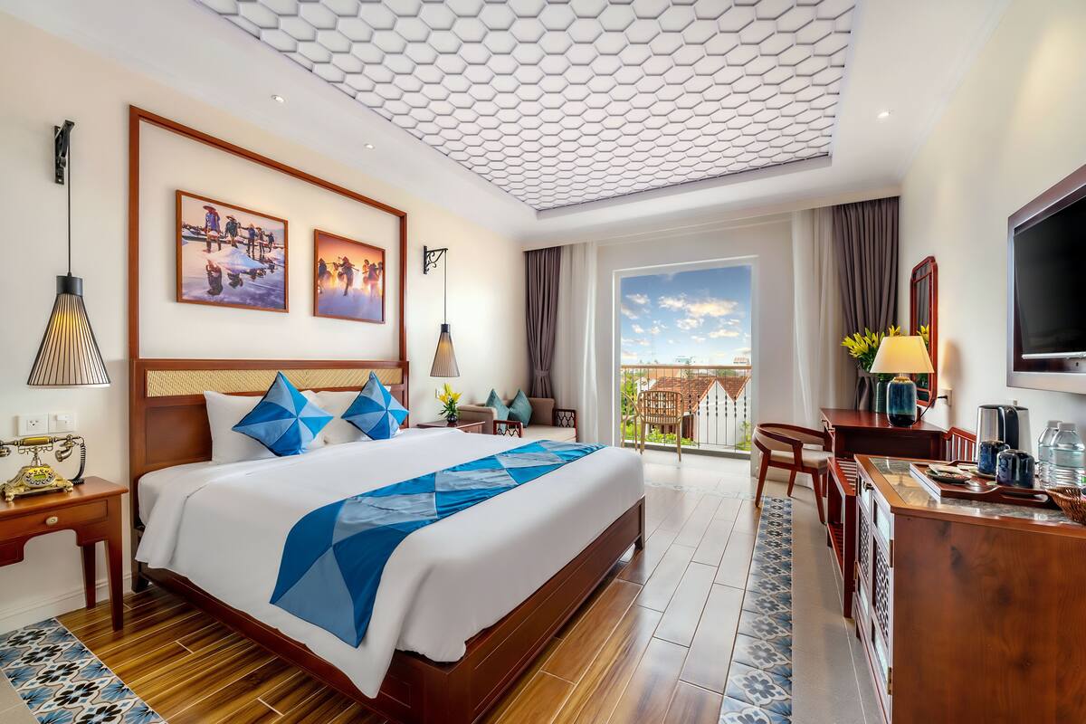 Een hotelkamer met een groot bed, een bureau, een televisie en een balkon met uitzicht.