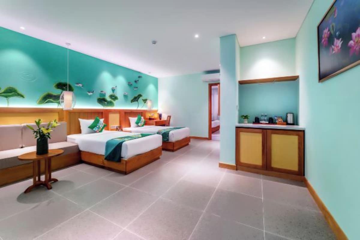 A hotel room with two beds, a small seating area, a kitchenette, and a bathroom.