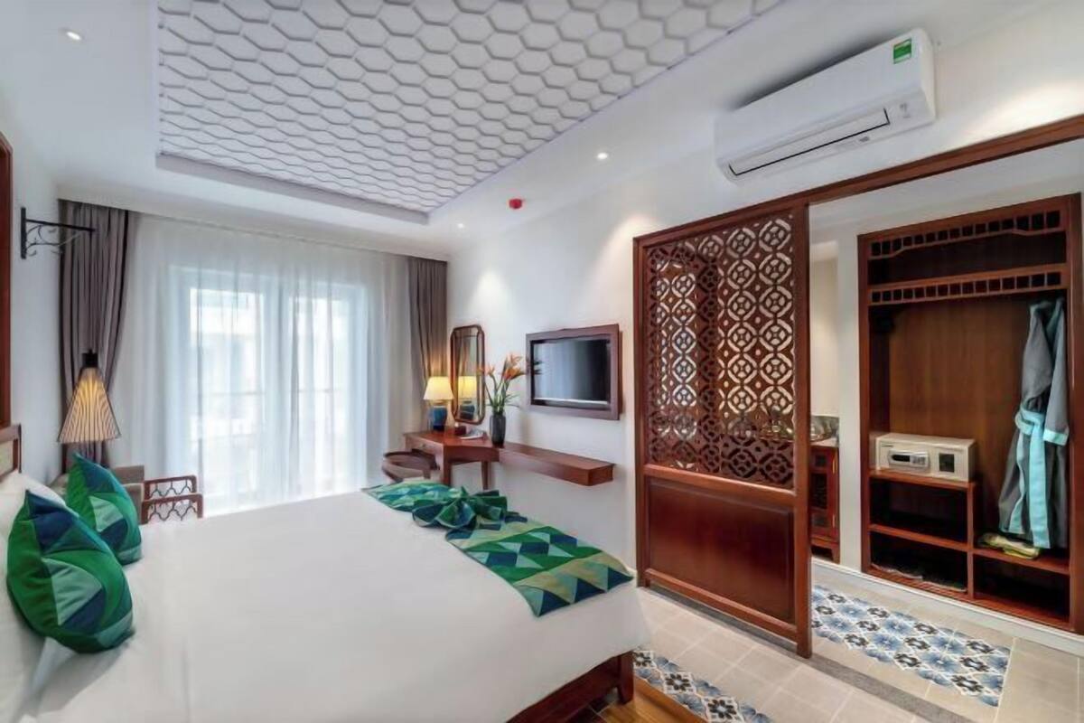 Hotelkamer met een bed, een televisie, een bureau, een kledingkast en een behanget plafond.