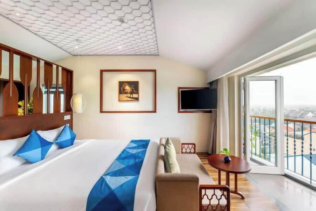 Hotelkamer met een groot bed, een bank, een klein tafeltje, een televisie en een balkon met uitzicht.