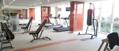 A gym with treadmills, weight machines, and a punching bag.