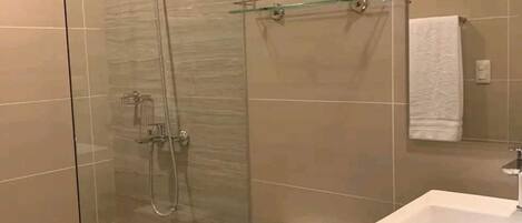 A modern bathroom with a glass-enclosed shower, a white toilet, and a sink with a mirror above it.