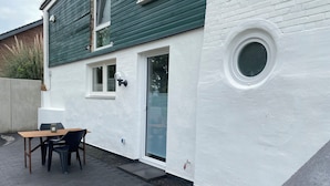 A modern house with a white exterior, a wooden deck, and a round window.