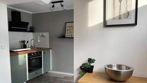 A modern kitchen with a wooden countertop, stainless steel appliances, and a potted plant.