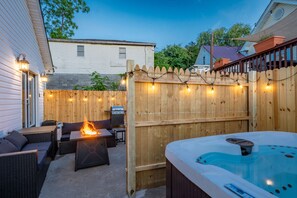 Un jardin avec un jacuzzi, un coin salon extérieur et des guirlandes lumineuses.