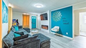 Uma sala de estar moderna com um sofá, uma mesinha, uma televisão e uma lareira.