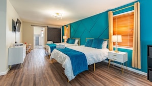 Quarto de hotel moderno com duas camas, uma escrivaninha, uma TV e uma janela grande com cortinas.