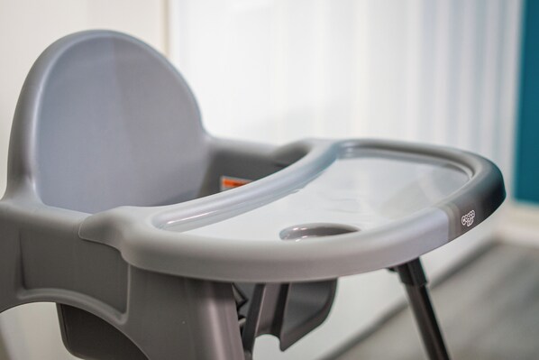 Une chaise haute pour bébé, dotée d’un plateau, d’une poignée et du logo de la marque.