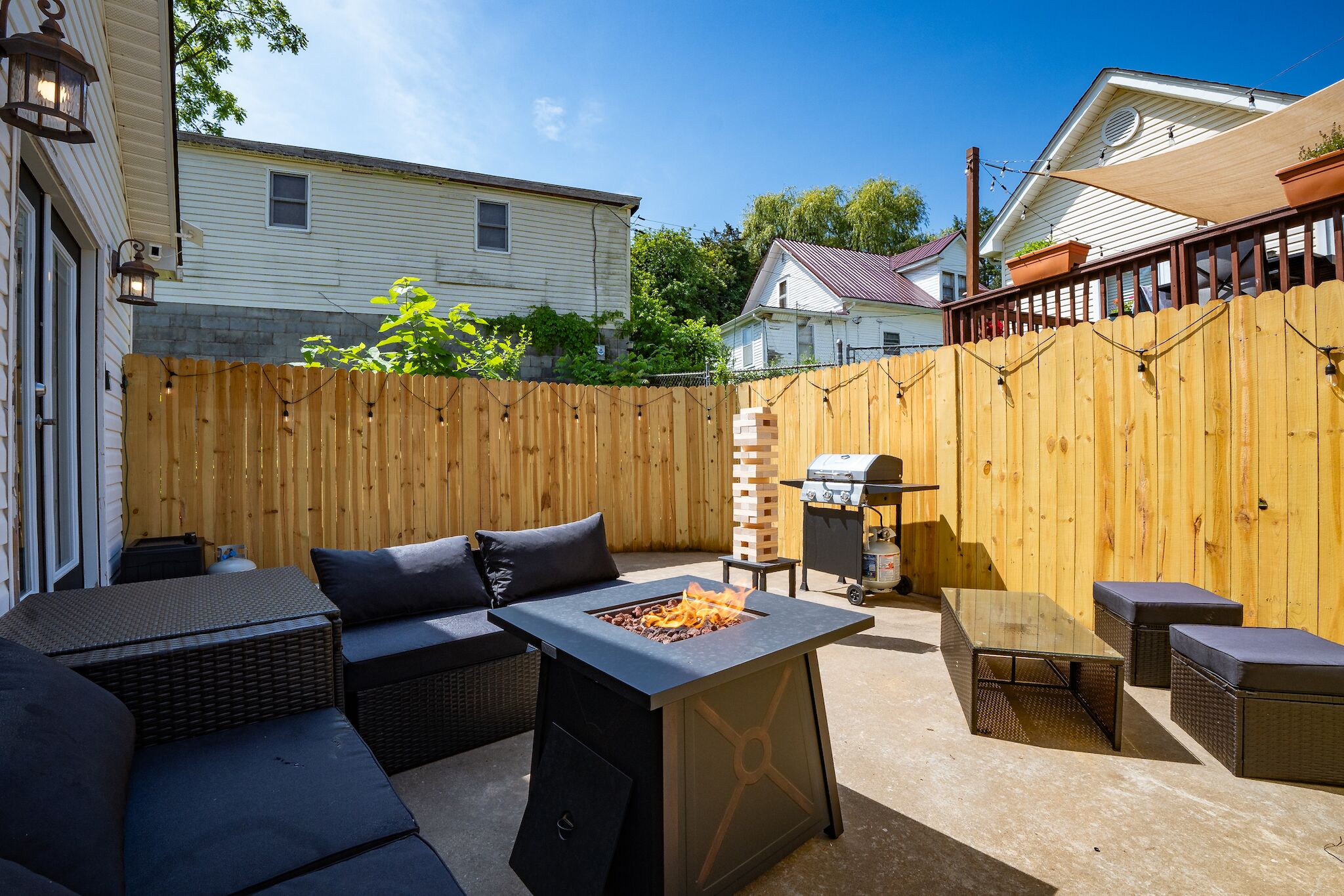 A backyard with a fire pit, outdoor seating, and a barbecue grill.
