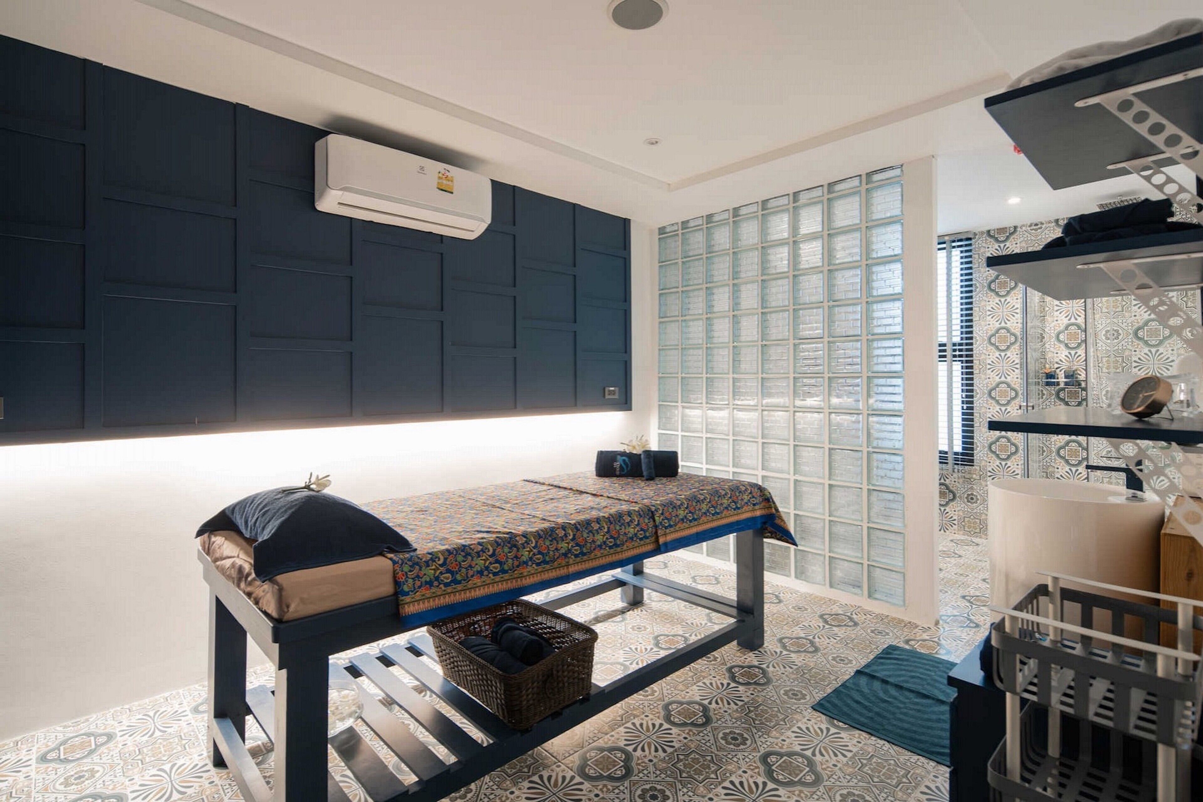 Una habitación pequeña y moderna con una cama, aire acondicionado de pared, piso estampado y ventana con vistas.