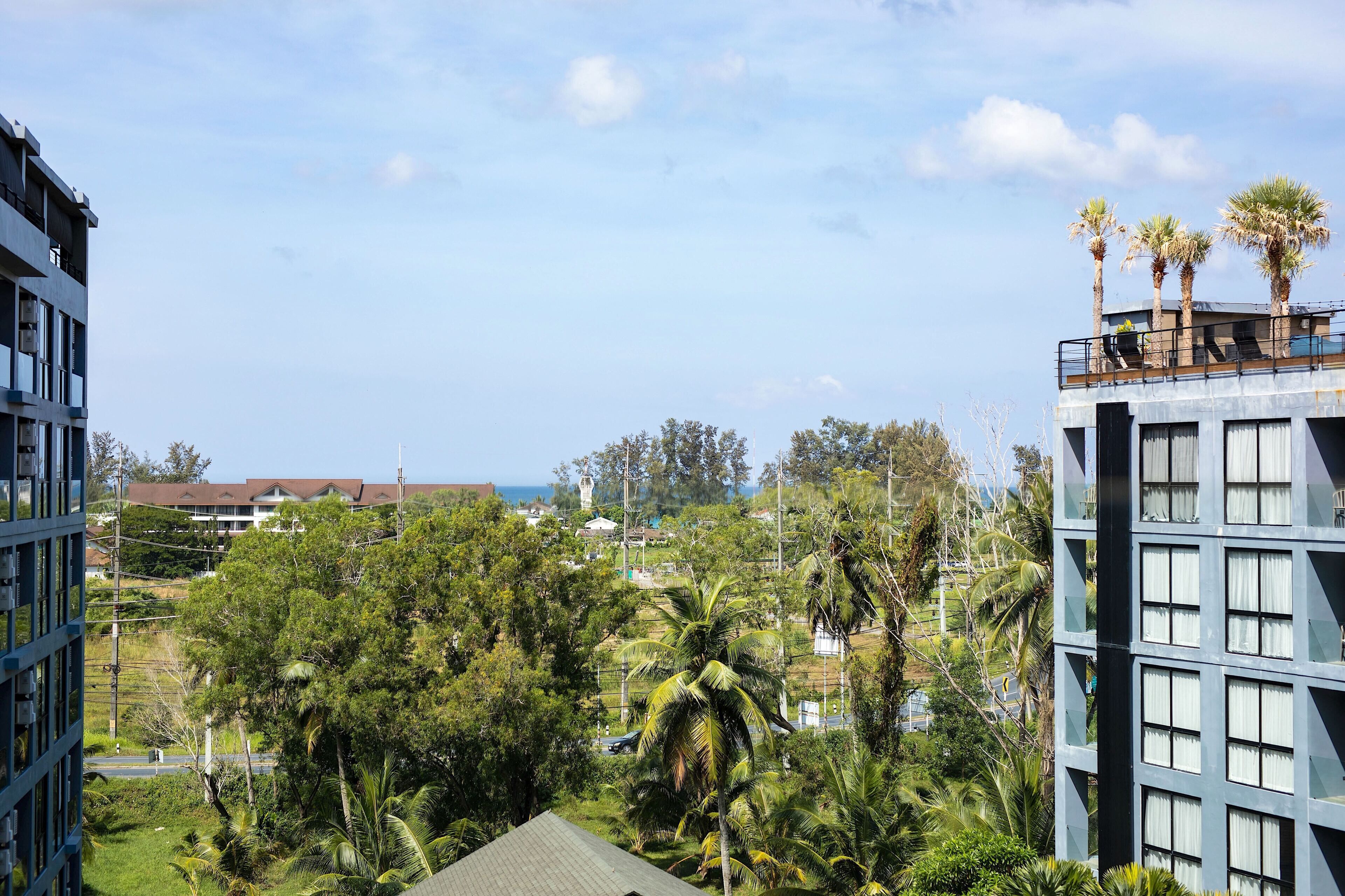 A modern building with multiple floors, surrounded by lush greenery and palm trees.
