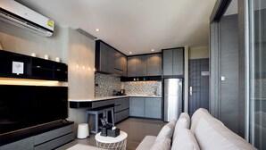 A modern kitchen with grey cabinets, a built-in oven, and a large refrigerator. There is a dining area with a white table and chairs.