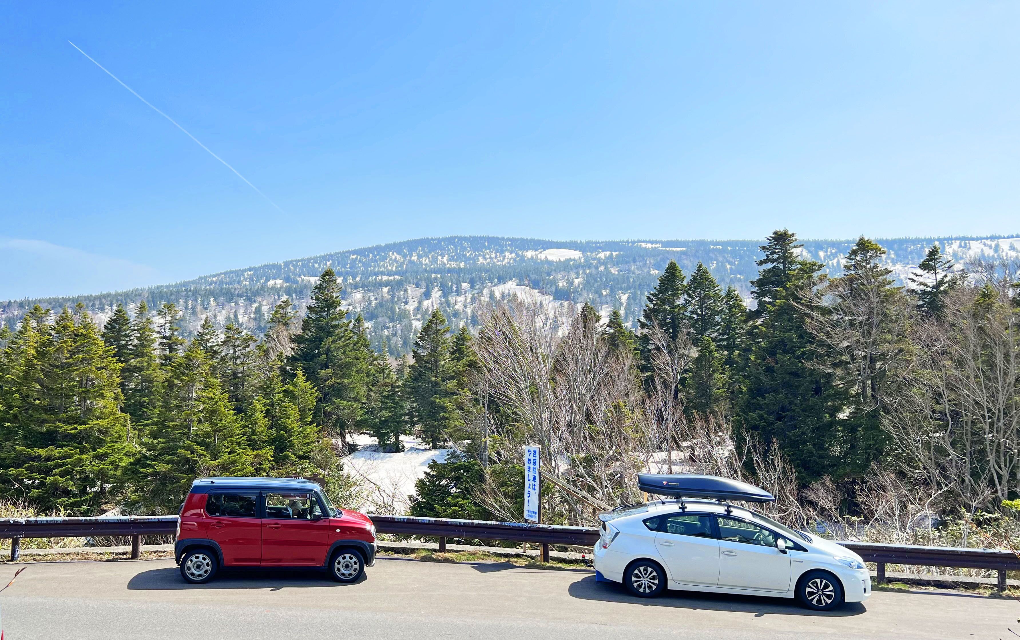 Dos coches aparcados en una carretera con un paisaje montañoso al fondo.
