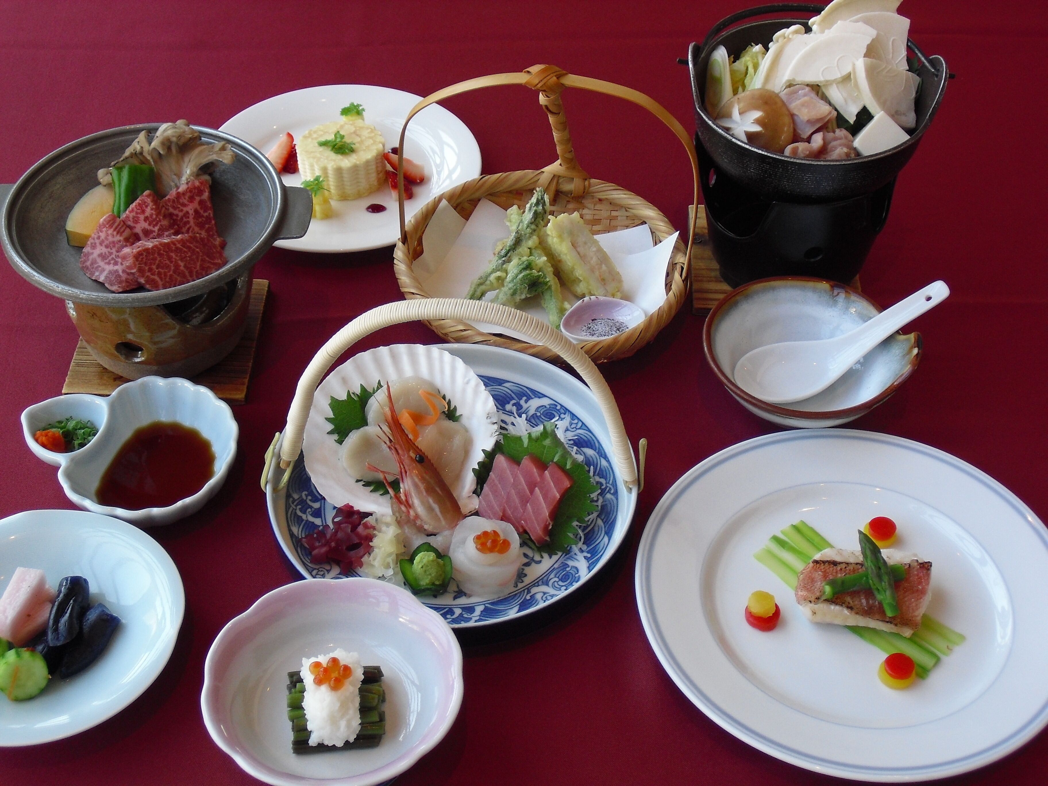 A variety of dishes on a table, including sushi, sashimi, and other seafood items.