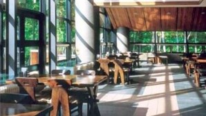 Un espace intérieur vaste et lumineux, doté de grandes fenêtres qui laissent entrer la lumière naturelle. Des tables et des chaises sont disposées pour permettre de prendre un repas ou de se détendre.