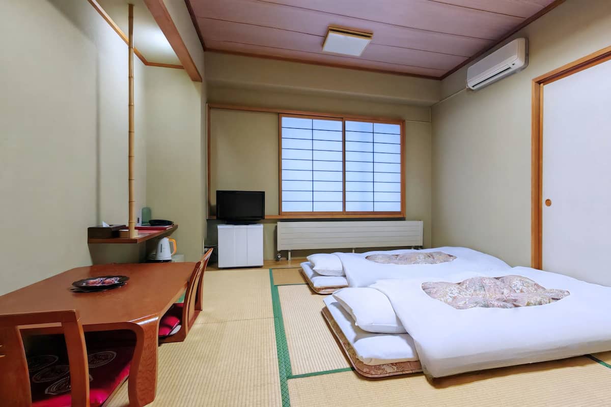 Habitación de hotel con dos camas, televisión, escritorio y ventana con vistas.