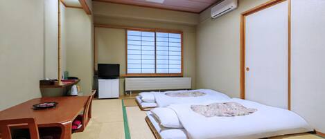 Habitación de hotel con dos camas, televisión, escritorio y ventana con vistas.