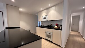Une cuisine moderne avec un plan de travail noir, des armoires blanches et un four encastré.