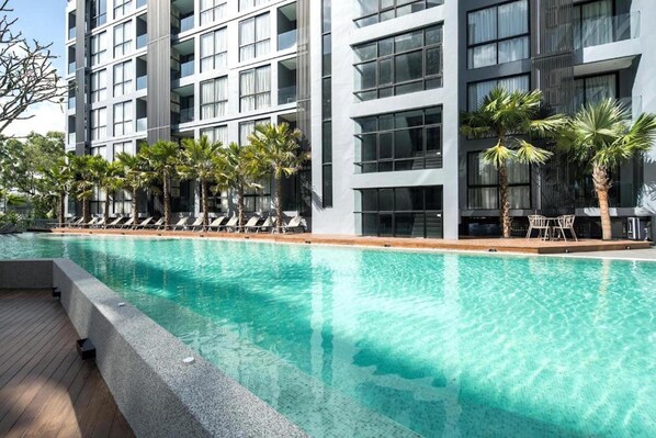 A modern hotel with a swimming pool, lounge chairs, and palm trees. - Chic Suite B704 at Citygate Kamala (Kamala)