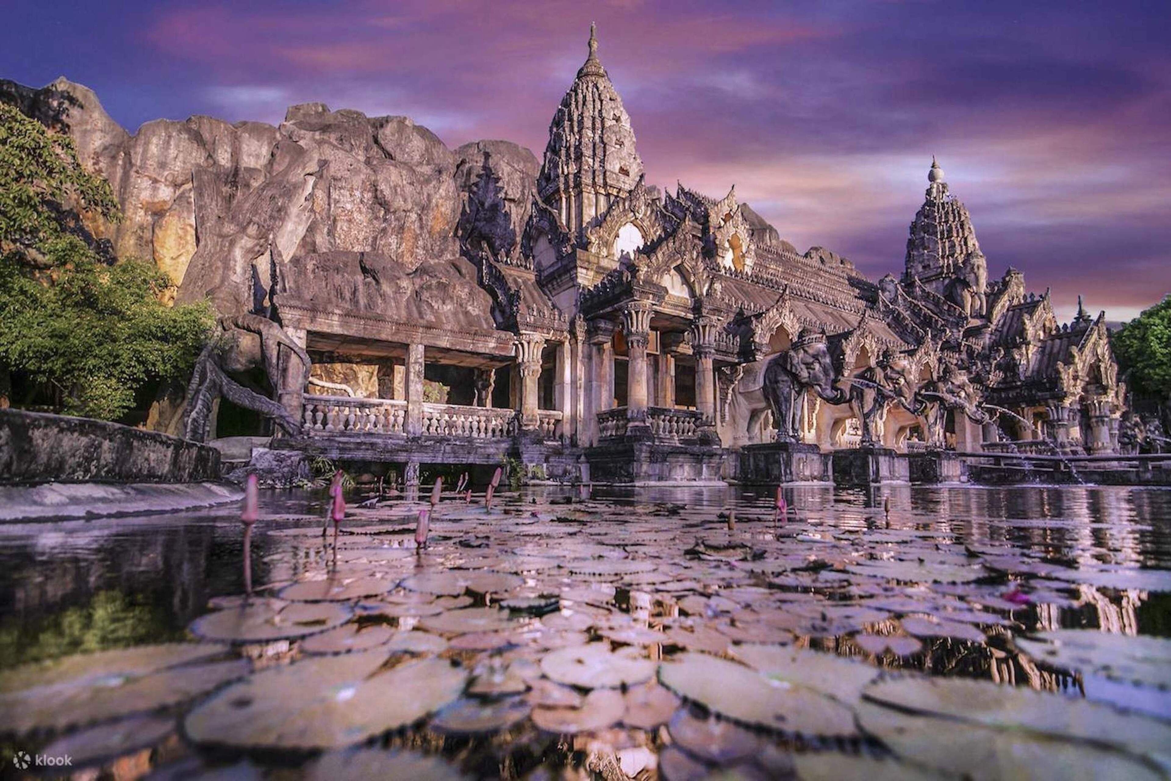 A temple complex with intricate architecture, a large reflecting pond, and lotus flowers.
