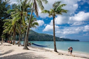 A beach with palm trees, a hammock, and a clear blue sky. - Chic Suite B704 at Citygate Kamala (Kamala)