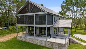 Een huis met twee verdiepingen, een overdekte veranda en een fundering van baksteen.