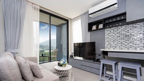 Un salon moderne avec un canapé, un téléviseur et un balcon offrant une vue agréable.