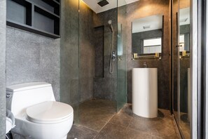 A modern bathroom with a glass-enclosed shower, a white toilet, and a pedestal sink. - Premier Hill View Suite P708 at Citygate (Kamala)
