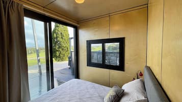 Un dormitorio con una cama grande, vistas al exterior a través de una ventana y una lámpara en el techo.