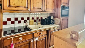A kitchen with wooden cabinets, a tiled backsplash, and a stove.