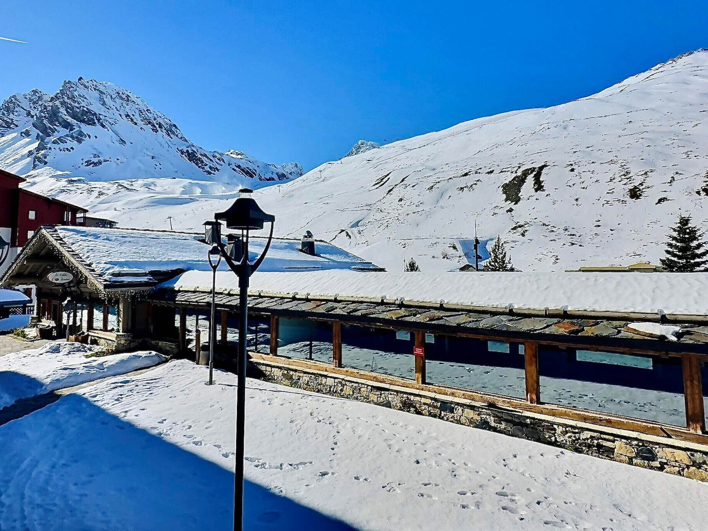 A snow-covered mountain with a wooden building and a lamppost in the foreground.