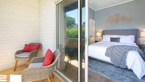 Une chambre à coucher avec un lit, une table de chevet et une chaise avec des coussins.