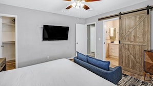 A bedroom with a bed, a TV, a ceiling fan, and a wardrobe. - Single Story Henderson 3BR Home, Hot tub, Sleeps 6 (Henderson)
