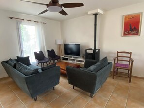 A living room with a sofa set, a television, a fireplace, and a ceiling fan.