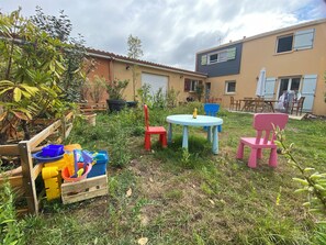 Ein Innenhof mit Gartenmöbeln, einem Tisch, Stühlen und Blumentöpfen.