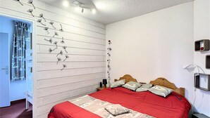 A bedroom with a bed, a wardrobe, and a wall with a floral pattern. - PMR Apartment in Corbier, Valley View, Balcony (Le Corbier)