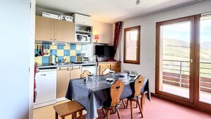 A kitchen with a dining table set for four, a television, and a view of the countryside through a large window. - PMR Apartment in Corbier, Valley View, Balcony (Le Corbier)