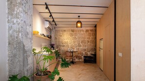 A narrow hallway with a stone wall, a wooden door, and a small table with chairs. - Vintage Eclectic Loft by Sea N' Rent (Tel Aviv)